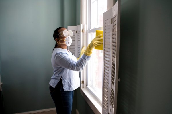 cleaning the inside of a house with a mask on